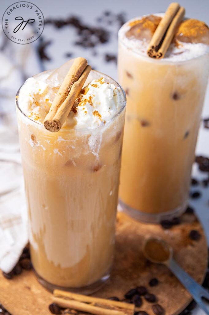 A side view of two glasses filled with pumpkin spice latte.