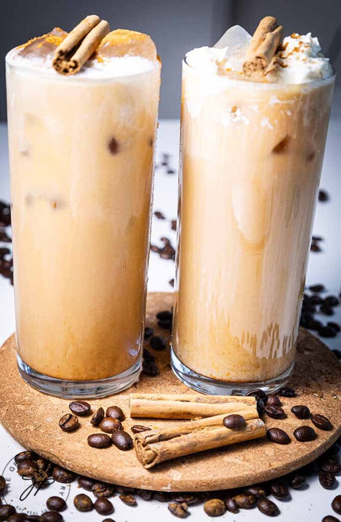 A front view of two glasses, side by side, filled with pumpkin spice latte.