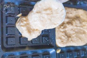 Pouring batter onto a waffle iron.