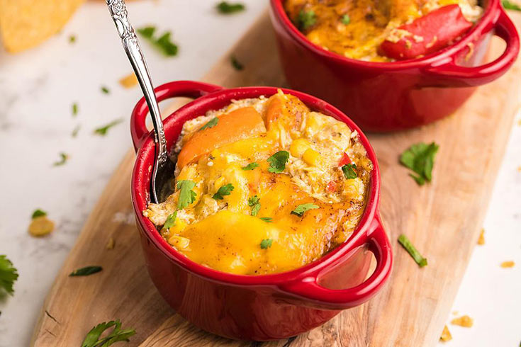 Two small, red casserole dishes filled with Super Easy Slow Cooker Chicken Enchilada Casserole.