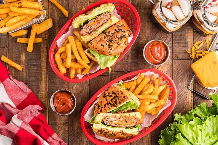 An overhead view of two burgers in red baskets with fries.