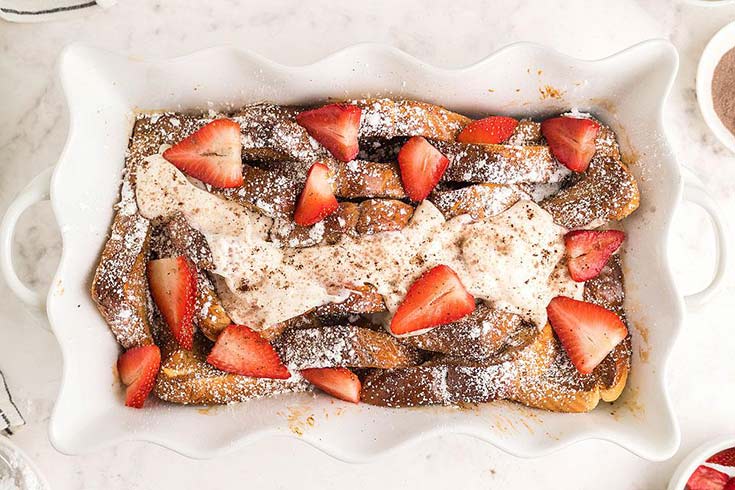 An overhead view of a white casserole dish filled with tiramisu french toast bake.