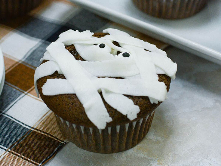 A single chocolate cupcake with white mummy frosting and googly eyes on top.