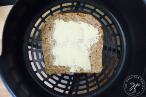 The second piece of bread topping an air fryer tuna melt in the air fryer basket.