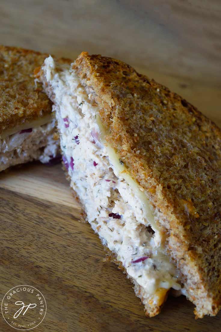 A long view of a half of a tuna melt laying on a cutting board.