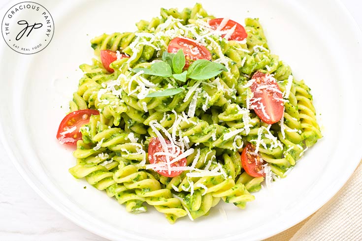 A white pasta bowl filled with Avocado Pasta, fresh grape tomatoes and grated parmesan cheese.