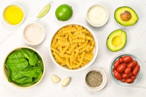 Avocado Pasta Recipe ingredients in individual bowls on a white surface.