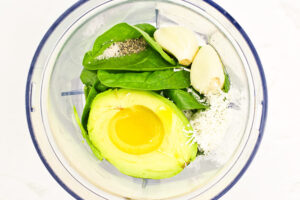 Avocado sauce ingredients in a blender tumbler.