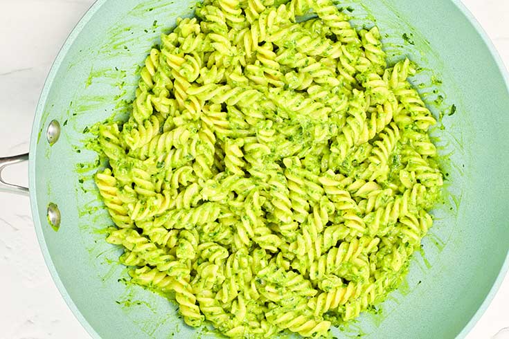 Rotini pasta tossed in sauce in a skillet.