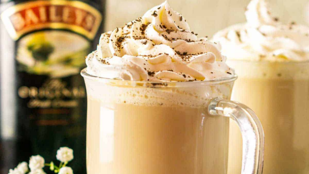 A glass mug filled with a Baileys latte and topped with whipped cream.
