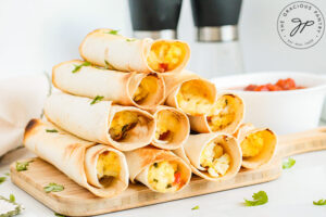 A stack of Healthy Breakfast Taquitos on a wood cutting board.