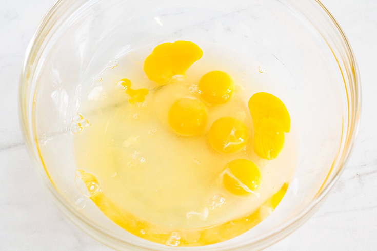 Cracked eggs in a glass mixing bowl.