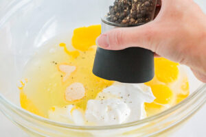 Seasoning eggs in a mixing bowl.