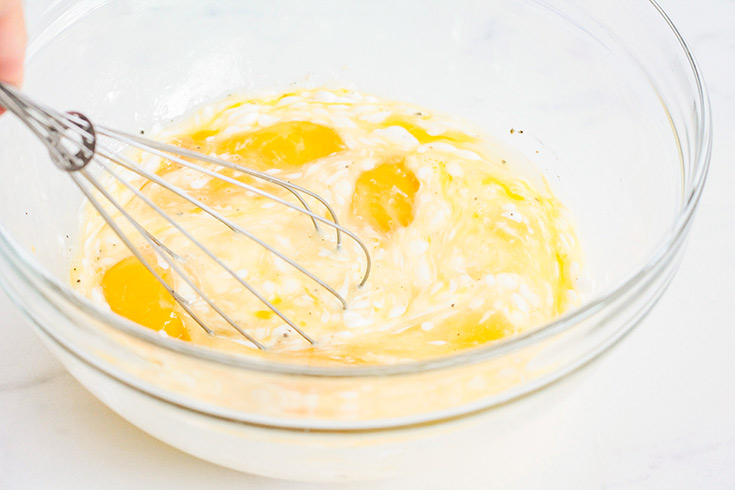 Whisking an egg mixture in a glass mixing bowl.