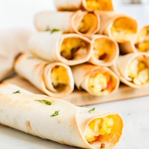 A single Healthy Breakfast Taquito lays in front of a stack of them.