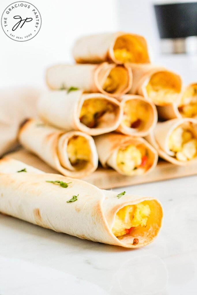 A single Healthy Breakfast Taquito lays in front of a stack of them.
