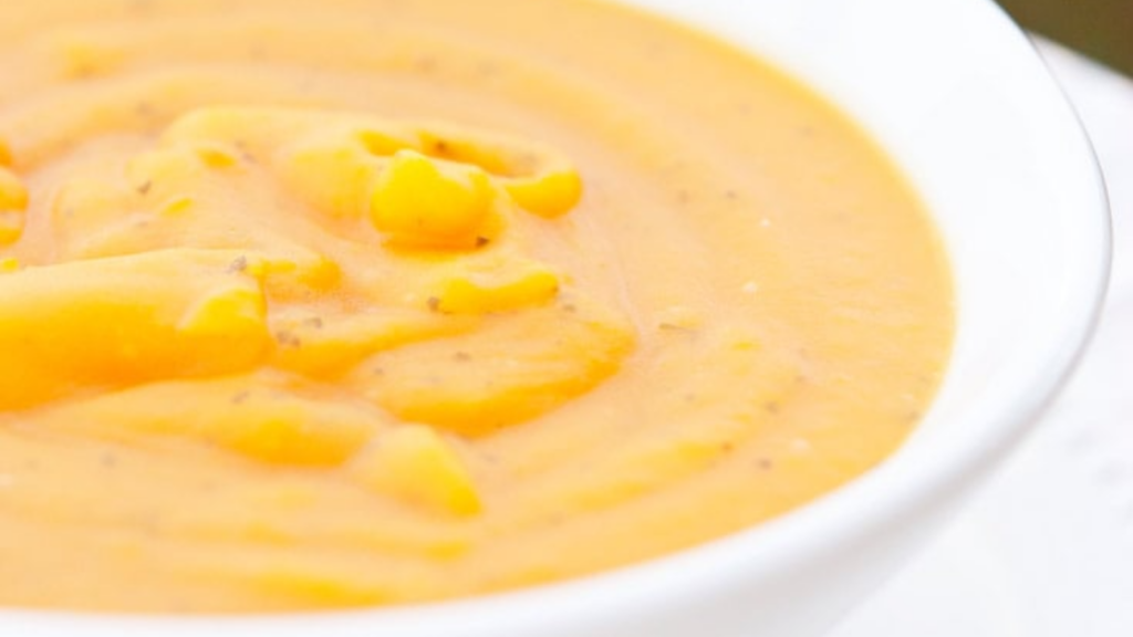 A closeup of a white bowl filled with butternut squash soup.