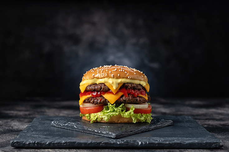 A fast food burger on a dark gray background.
