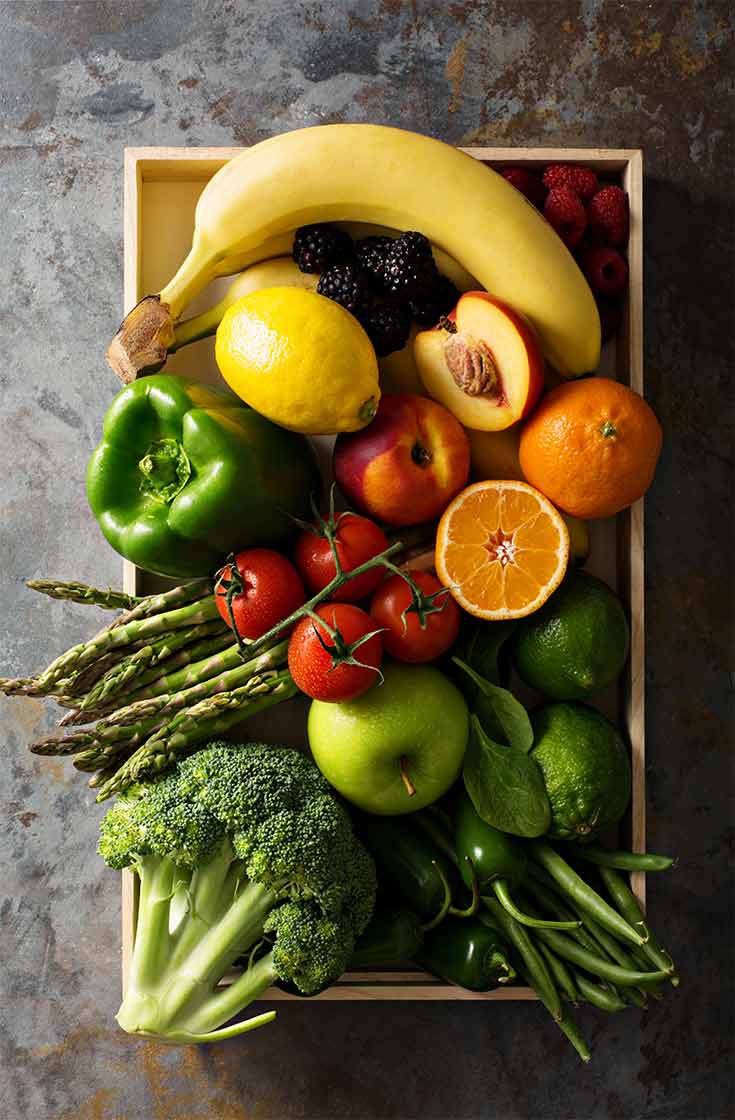 An overhead view of a wood crate holding fresh fruits and vegetables.