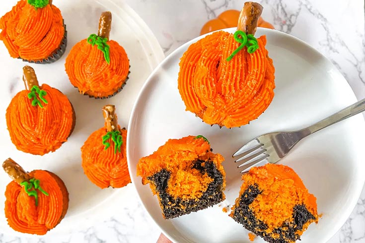 An overhead view of pumpkin cupcakes on a white plate and platter.