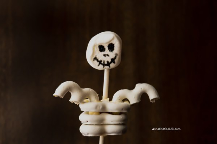 A skeleton cupcake topper on a dark, brown background.