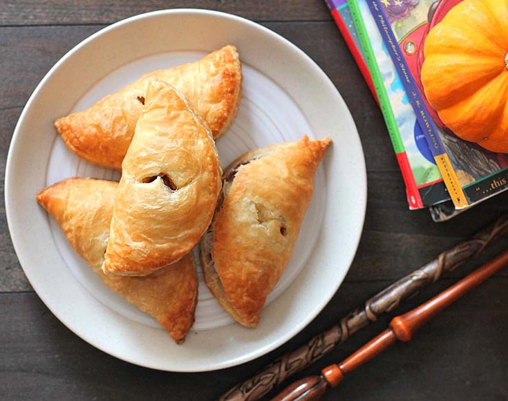 Four pumpkin pasties on a white plate.