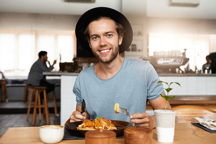 A man wearing a hat at the dinner table.