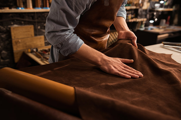A man smoothing out a piece of leather over a table.