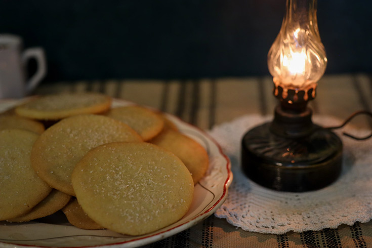 Lemon snaps on a plate next to an old fashioned oil lamp.