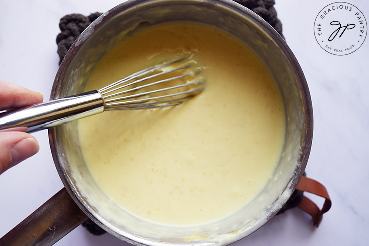 Melted, finished cheese sauce in a pot with a whisk.