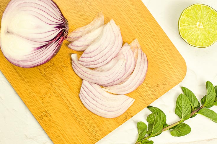 Cut red onions lay on a cutting board.