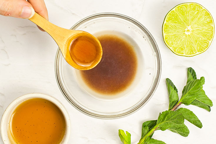 A spoonful of oil being added to the mango salad dressing.