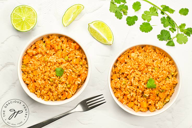 An overhead view of two white bowls filled with Mexican rice.