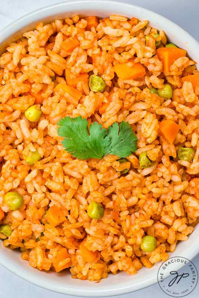 A closeup overhead view of a white bowl filled with Mexican rice.