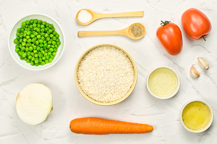 Mexican rice ingredients on a white surface in individual bowls.