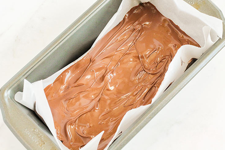 The chocolate spread evenly over the bar base in a parchment-lined loaf pan.