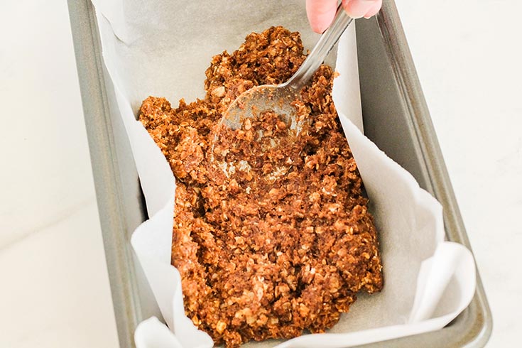 Spreading the base over the bottom of a parchment-lined loaf pan.