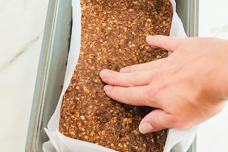 Pressing the bar base flat in a parchment-lined loaf pan.