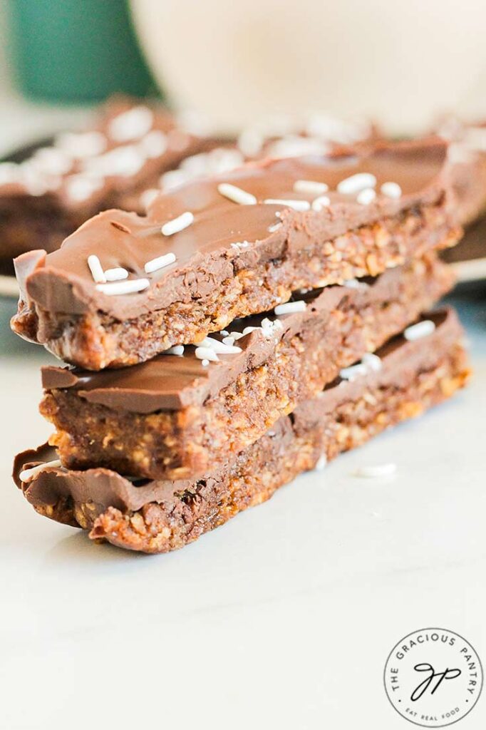 Three No Bake Pumpkin Protein Bars stacked up on a white surface.