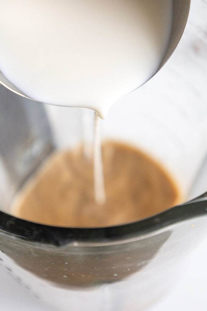 Adding milk to coffee in a blender cup.