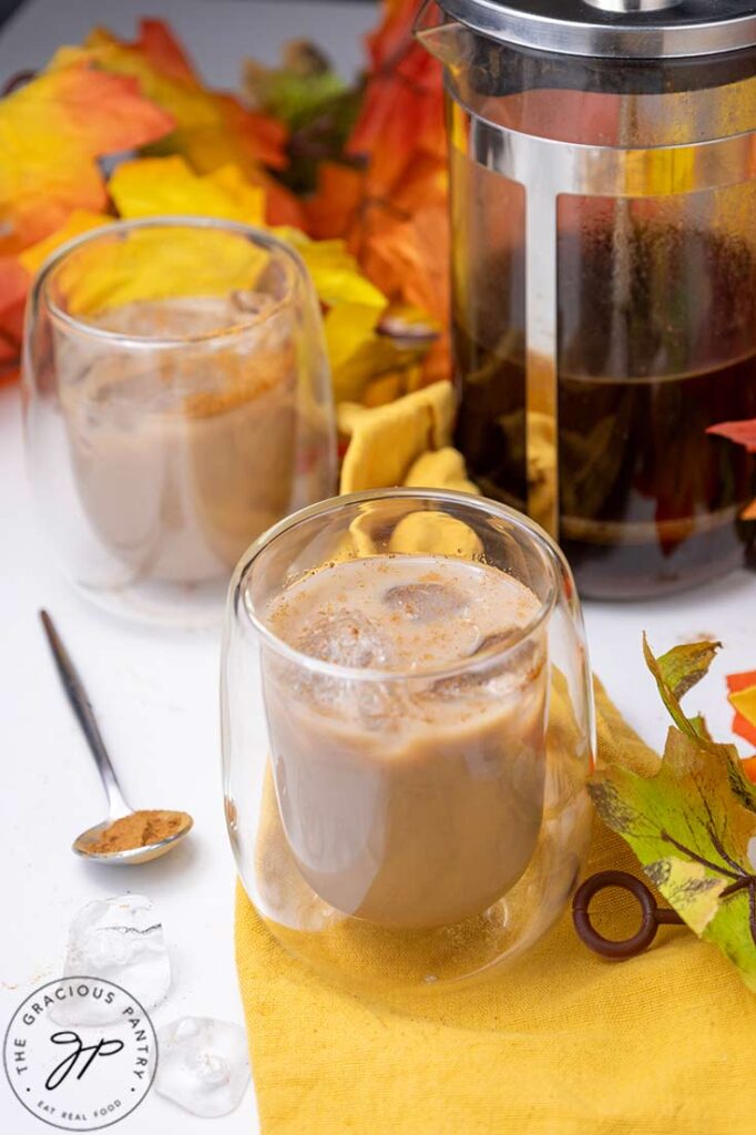 A front view of two clear cups filled with ice and Pumpkin Iced Coffee.