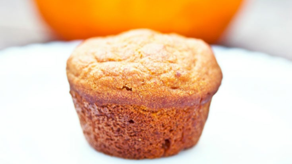 A closeup of a pumpkin mini muffin on a white plate.