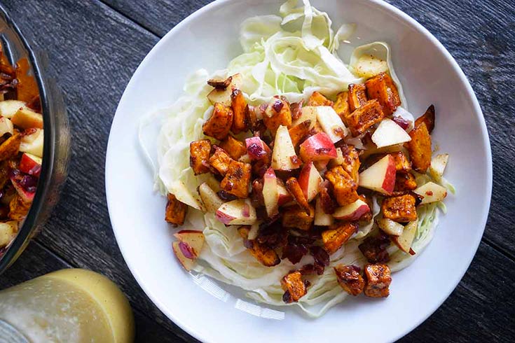 An overhead view of a white bowl filled with roasted sweet potato salad.