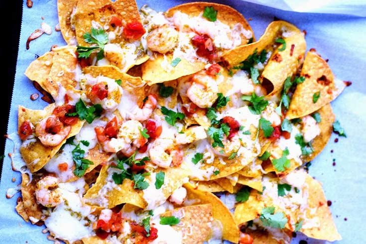 An overhead view of shrimp nachos on parchment paper.