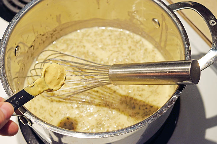 Adding mustard to sauce in a pot.