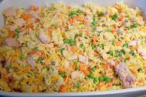 Spreading casserole filling over the bottom of a casserole dish.