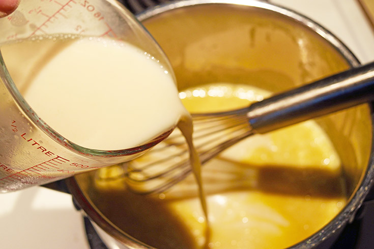 Adding milk to melted butter in a pot.