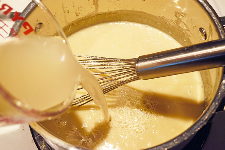 Adding chicken broth to butter in a pot.