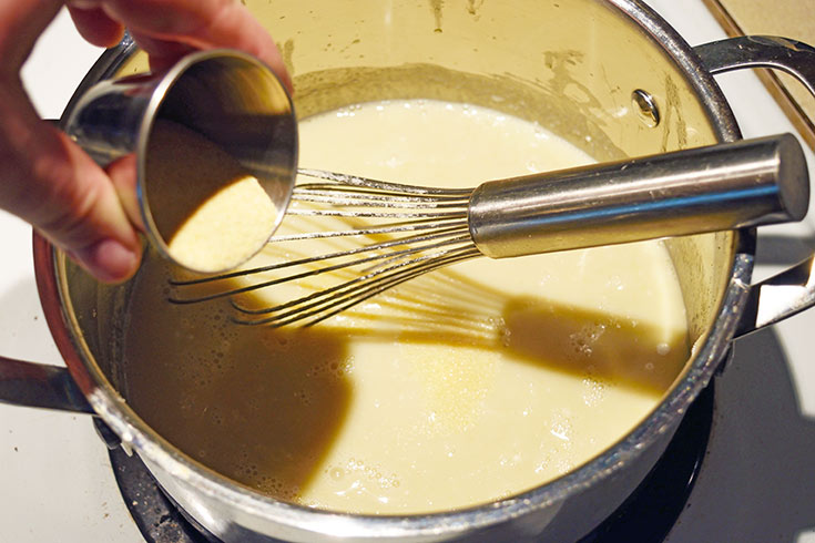 Adding spices to sauce in a pot.