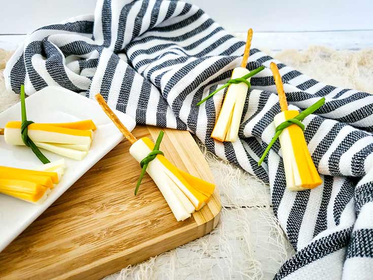 Several witches broom snacks laying on a cutting board and kitchen towel.